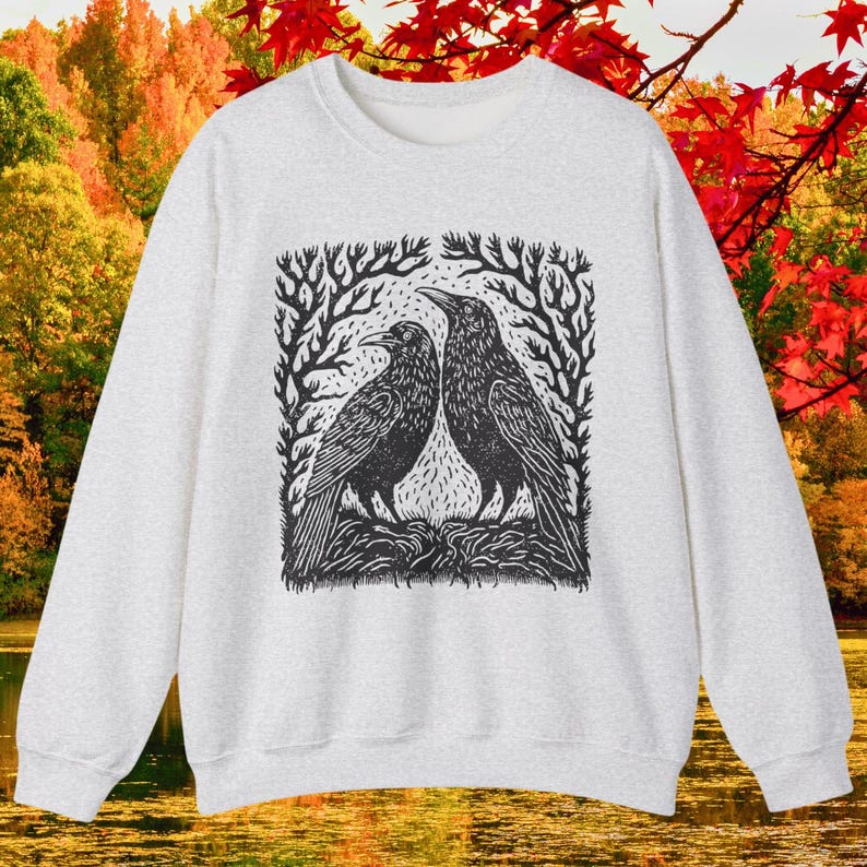 May include: A gray sweatshirt with a black and white illustration of two crows facing each other in a forest setting.