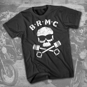 Puede incluir: Camiseta negra con un diseño blanco de calavera y huesos cruzados. La calavera lleva gafas de sol y los huesos cruzados están hechos de pistones de motor. El texto "B.R.M.C." está por encima de la calavera.