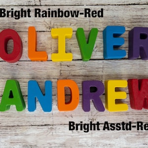 May include: The names OLIVER and ANDREW spelled out in colorful plastic letters. The letters are arranged in two rows. The top row is red, orange, yellow, green, blue, and purple. The bottom row is green, blue, orange, purple, yellow, and red. The text "Bright Rainbow-Red" is above the top row of letters. The text "Bright Assstd-Red" is below the bottom row of letters.
