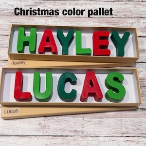May include: Two boxes with the names "HAYLEY" and "LUCAS" spelled out in red and green wax letters. The boxes are made of brown cardboard and have a white background.