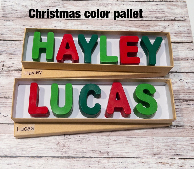May include: Two boxes with the names "HAYLEY" and "LUCAS" spelled out in red and green wax letters. The boxes are made of brown cardboard and have a white background.