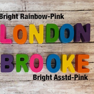 May include: The name "LONDON BROOKE" spelled out in colorful foam letters. The letters are arranged in two rows. The top row is "LONDON" in rainbow colors. The bottom row is "BROOKE" in purple, green, pink, blue, yellow, and pink.