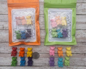 May include: Two clear plastic bags with resealable zippers, each containing a set of 8 colorful bear-shaped crayons. The crayons are arranged in a rainbow pattern. The bags are on a wooden surface with 16 additional crayons laid out in a rainbow pattern.