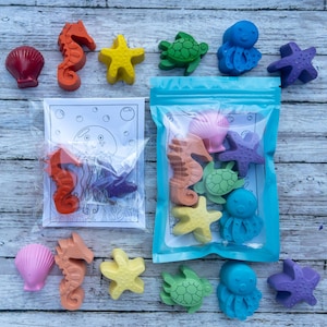 May include: A collection of sea-themed wax crayons shaped like seahorses, starfish, turtles, octopuses, and seashells in various colors. The set includes a clear plastic bag containing several crayons and a coloring card with a jellyfish illustration.