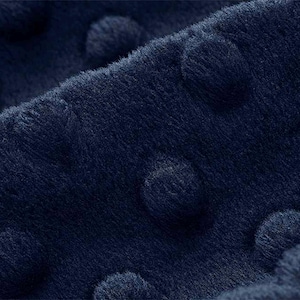May include: Close-up of a dark blue fabric with a textured, raised dot pattern.
