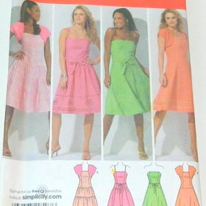 May include: Simplicity sewing pattern 4224 featuring dresses in various styles and colors. The pattern includes sizes 14, 16, 18, 20, and 22. The image shows the dresses in pink, green, and orange. The Simplicity logo is visible.