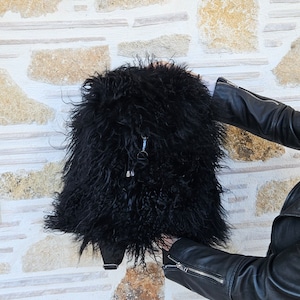 Könnte beinhalten: Ein schwarzer, flauschiger Rucksack mit Reißverschluss und silbernem Reißverschluss-Zipper.