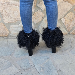 May include: Black fur-trimmed ankle boots with a chunky heel. The boots are made of black leather and have a fluffy black fur trim around the top of the boot.