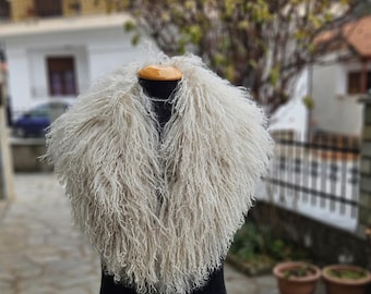 May include: A fluffy white faux fur collar with long, shaggy strands. The collar is displayed on a black mannequin.