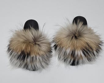 May include: A pair of black faux fur slides with a fluffy, multi-colored fur pom-pom on each slide.