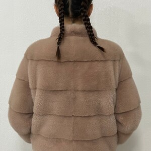 K&ouml;nnte beinhalten: Eine hellbraune Pelzjacke mit Stehkragen. Die Jacke ist aus weichem, pl&uuml;schigem Pelz und hat eine lockere Passform.