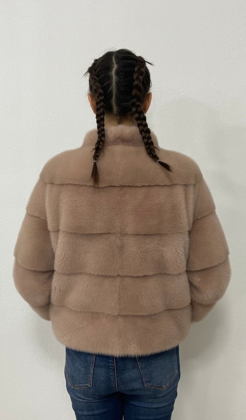 K&ouml;nnte beinhalten: Eine hellbraune Pelzjacke mit Stehkragen. Die Jacke ist aus weichem, pl&uuml;schigem Pelz und hat eine lockere Passform.