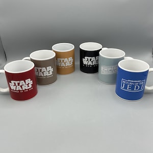 May include: Six white ceramic mugs with Star Wars movie titles and logos. The mugs are arranged in a semi-circle on a gray surface. The mugs feature the titles "Star Wars: Revenge of the Sith", "Star Wars: Phantom Menace", "Star Wars: Attack of the Clones", "Star Wars: A New Hope", "The Empire Strikes Back", and "Star Wars: Return of the Jedi".
