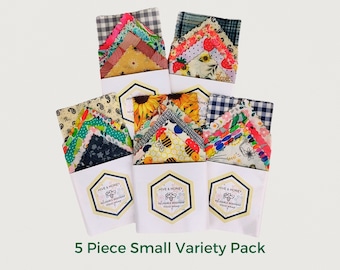 May include: A set of five small reusable beeswax food wraps in a variety of colorful patterns. The wraps are packaged in white boxes with the brand name "Hive & Honey" printed on them. The text "5 Piece Small Variety Pack" is printed below the boxes.