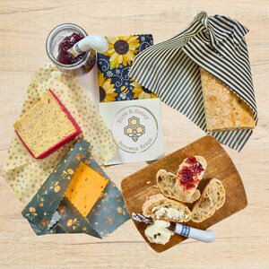 Three beeswax wraps being used to cover bread and cheeses.