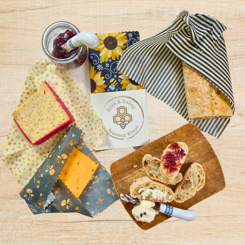 Three beeswax wraps being used to cover bread and cheeses.