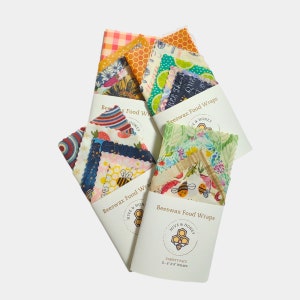 Four examples of how our variety pack of beeswax wraps are packaged. Shows a mix of patterns and colors folded with the logo and care & use sleeve.