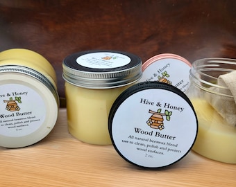 May include: Three glass jars of wood butter, a natural beeswax blend for cleaning, polishing, and protecting wood surfaces. The jars are labeled "Hive & Honey Wood Butter" and have a beehive logo. The jars are 2 oz and 6 oz.