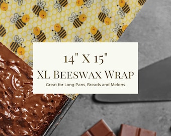 May include: An XL beeswax wrap, 14" x 15", with a yellow honeycomb pattern and illustrated bees. The wrap is designed for long pans, breads, and melons. The image also shows a chocolate dessert and chocolate bars.