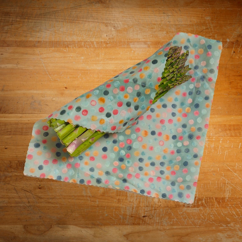 Asparagus being wrapped up for storage in our polka dot patterned beeswax wrap.