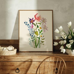 May include: A framed print of a watercolour painting featuring a bouquet of flowers in shades of pink, purple, blue, green, and yellow. The flowers include orchids, daffodils, and other blooms.