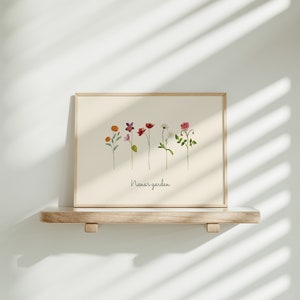 May include: A framed print with a watercolor illustration of a row of colorful flowers with the text "Nana's garden" at the bottom.