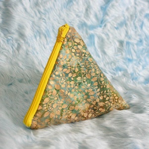 May include: A triangular zippered pouch with a green and gold floral pattern and a bright yellow zipper.