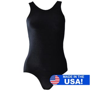 May include: A solid black bodysuit with a scoop back and sleeveless design. The garment is form-fitting and made of a smooth, opaque fabric. The image includes a blue banner with the text "MADE IN THE USA!" and an American flag.