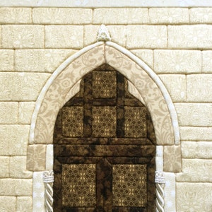 May include: A beige fabric wall with a brown fabric arched doorway. The doorway is made of squares and has a decorative pattern.