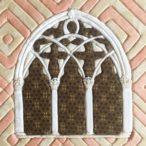 May include: A white fabric archway with a brown patterned fabric background. The archway has a decorative design with multiple arches and a pointed top.