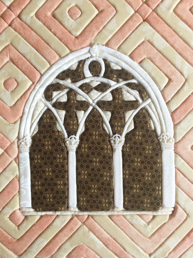 May include: A white fabric archway with a brown patterned fabric background. The archway has a decorative design with multiple arches and a pointed top.