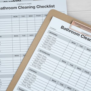 May include: Bathroom cleaning checklists on a clipboard and loose sheets. The checklists are printed in black and white and include sections for morning, afternoon, evening, and night. The clipboard has a copper-colored clip.