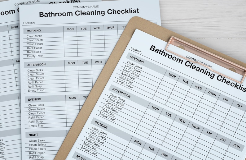 May include: Bathroom cleaning checklists on a clipboard and loose sheets. The checklists are printed in black and white and include sections for morning, afternoon, evening, and night. The clipboard has a copper-colored clip.