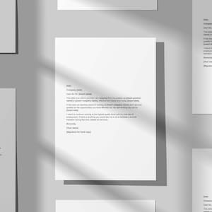 May include: Several white sheets of paper with text are arranged on a gray surface. The papers appear to be resignation letters, with text including "Dear Mr/Ms" and "Company Name". The image has soft shadows.