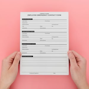 Pu&ograve; includere: Un modulo bianco di carta con il titolo "EMPLOYEE EMERGENCY CONTACT FORM" e campi per le informazioni del dipendente, i contatti di emergenza primari e secondari e informazioni aggiuntive. Il modulo &egrave; tenuto da due mani.