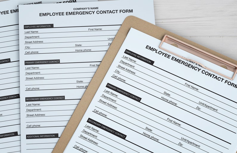 Pu&ograve; includere: Un modulo bianco di carta con il titolo "Modulo di contatto di emergenza per i dipendenti" su una clipboard marrone. Il modulo contiene campi per le informazioni sui dipendenti, il contatto di emergenza principale e il contatto di emergenza secondario.