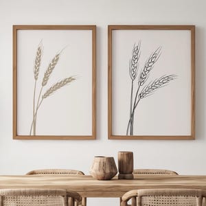 Peut inclure: Deux cadres muraux présentant des dessins au trait minimalistes d'épis de blé en brun clair et gris foncé, disposés au-dessus d'une table à manger rectangulaire en bois avec quatre chaises assorties dotées d'assises en canne et dossiers incurvés.