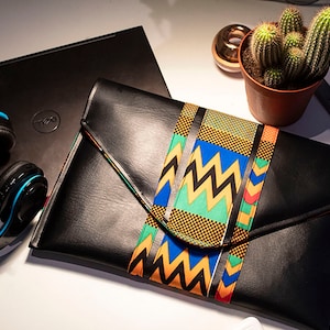 May include: Black leather clutch with a colourful patterned flap. The pattern features yellow, blue, green, red and black geometric shapes.