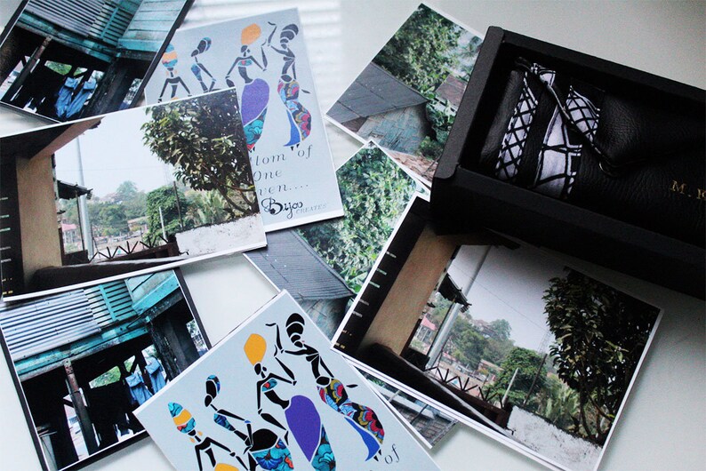 May include: A set of postcards featuring colourful illustrations of women in traditional African clothing. The postcards have a white background and feature the text "From one woman... Byjo Designs".