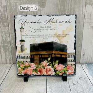 May include: A black slate plaque with a watercolor image of the Kaaba in Mecca, Saudi Arabia. The plaque has the text "Umrah Mubarak" and "Mum & Dad" with the date "October 2024 | 1446 AH". The text continues with a prayer for a blessed Umrah pilgrimage.