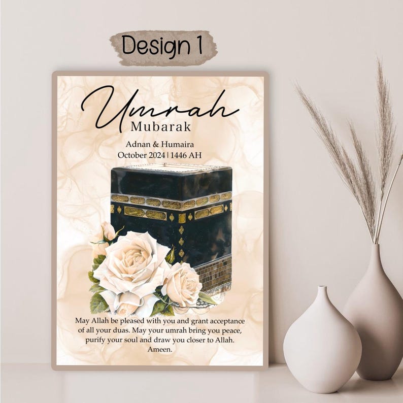 Op de afbeelding: Een digitale kunstprint met een witte achtergrond en een zwart-gouden afbeelding van de Kaaba, het kubusvormige gebouw in het centrum van de heiligste moskee van de islam in Mekka, Saoedi-Arabi&euml;. De afbeelding is omringd door witte rozen. De tekst "Umrah Mubarak" is in een decoratief lettertype bovenaan de print geschreven. De tekst "Adnan & Humaira" en "Oktober 2024 | 1446 AH" is onder de afbeelding geschreven. De tekst "Moge Allah tevreden met je zijn en je de acceptatie van al je smeekbeden schenken. Moge je umrah je vrede brengen, je ziel reinigen en je dichter bij Allah brengen. Amin." is onderaan de print geschreven.