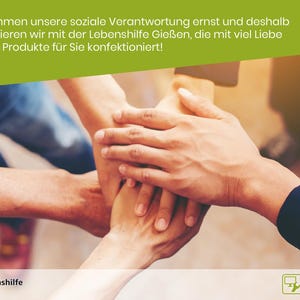 Pu&ograve; includere: Quattro mani sono impilate l'una sull'altra, a simboleggiare il lavoro di squadra e la collaborazione. Il testo "Wir nehmen unsere soziale Verantwortung ernst und deshalb kooperieren wir mit der Lebenshilfe Gie&szlig;en, die mit viel Liebe unsere Produkte f&uuml;r Sie konfektioniert!" &egrave; visualizzato sopra le mani. Il testo "Lebenshilfe Gie&szlig;en" &egrave; visualizzato in un cerchio nella parte inferiore sinistra dell'immagine. Il testo "Reha Werkstatt Mitte" &egrave; visualizzato in un rettangolo nella parte inferiore destra dell'immagine.
