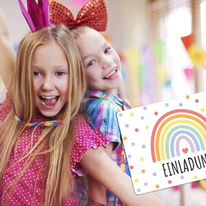May include: Two girls wearing party hats and holding colorful streamers. One girl is holding a rainbow-themed invitation card with the word "EINLADUNG" on it.