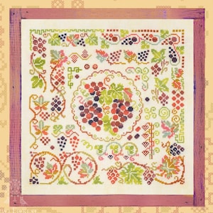 May include: A cross-stitch pattern featuring a variety of grapes and vines in shades of green, red, and purple. The pattern is framed in a wooden frame with a pink border.