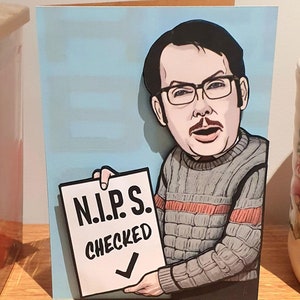 May include: A humorous greeting card with a cartoon illustration of a man in glasses and a grey jumper. The man holds a sign that says "N.I.P.S. CHECKED" with a tick. The background is a light blue colour.
