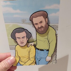 May include: Greeting card featuring a cartoon illustration of two men. One man has a beard and is wearing a yellow long-sleeve shirt and blue jeans. The other man is wearing a yellow long-sleeve shirt and blue jeans. The background shows a blue sky.