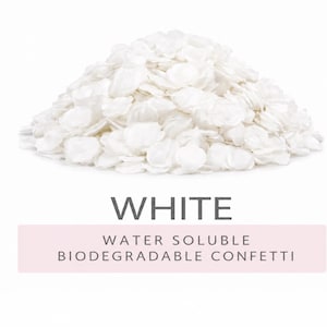 A pile of round, white confetti pieces. Below the pile, the text reads WHITE followed by WATER SOLUBLE BIODEGRADABLE CONFETTI on a light pink rectangular background. The confetti appears thin, flat, and uniform in colour. its is water soluble and biodegradable ideal for confetti wedding decor.