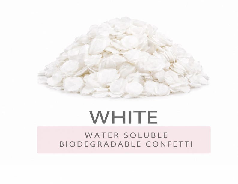A pile of round, white confetti pieces. Below the pile, the text reads WHITE followed by WATER SOLUBLE BIODEGRADABLE CONFETTI on a light pink rectangular background. The confetti appears thin, flat, and uniform in colour. its is water soluble and biodegradable ideal for confetti wedding decor.