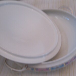 May include: A white oval serving dish with a lid. The dish has a pink and blue patterned border.