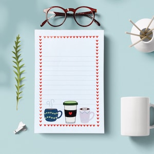 May include: A white notepad with red heart borders and lined paper. The notepad has a graphic of three cups of coffee, one with a red heart, one with green and white stripes, and one with a blue and white pattern.